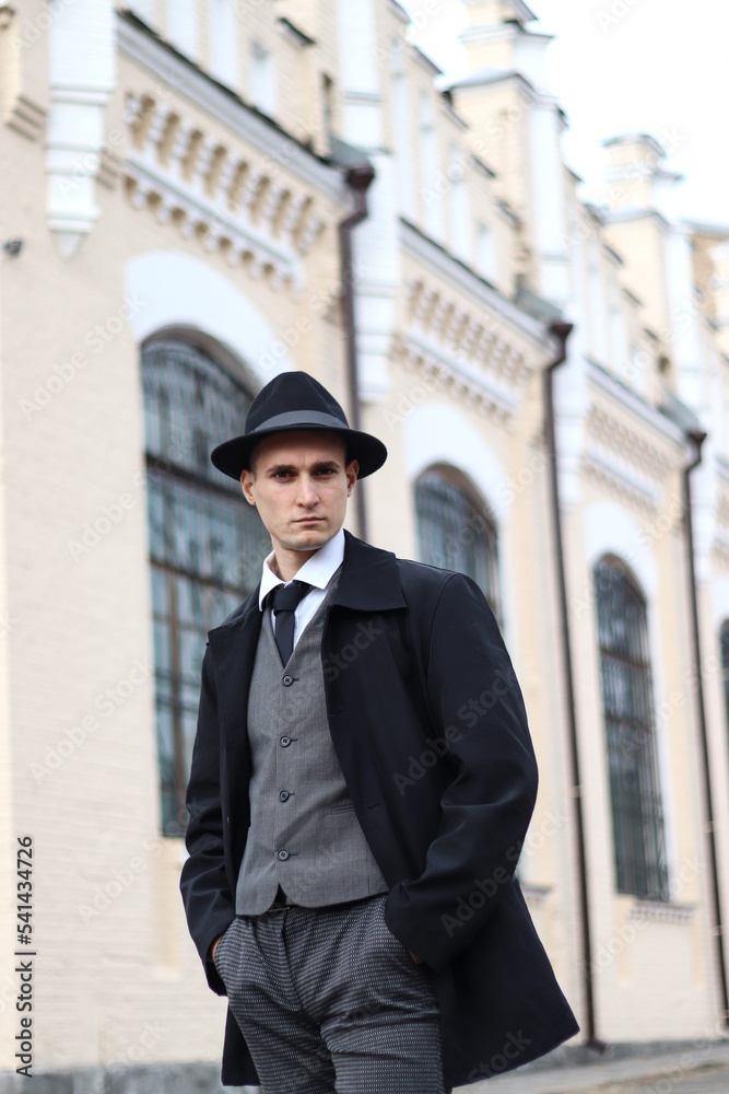 Men's photo shoot in a classic plaid suit and a hat against the backdrop of an old building. Men's photo shoot in a classic plaid suit and a hat against the backdrop of an old building.
