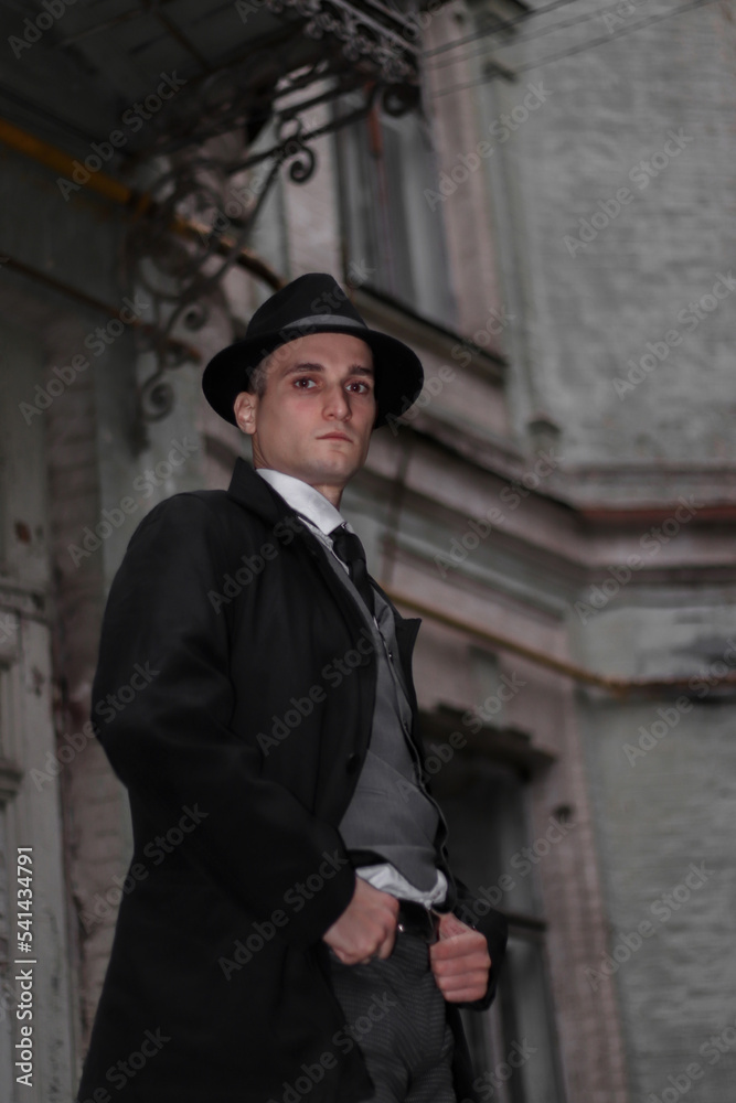 Men's photo shoot in a classic plaid suit and a hat against the backdrop of an old building. Men's photo shoot in a classic plaid suit and a hat against the backdrop of an old building.