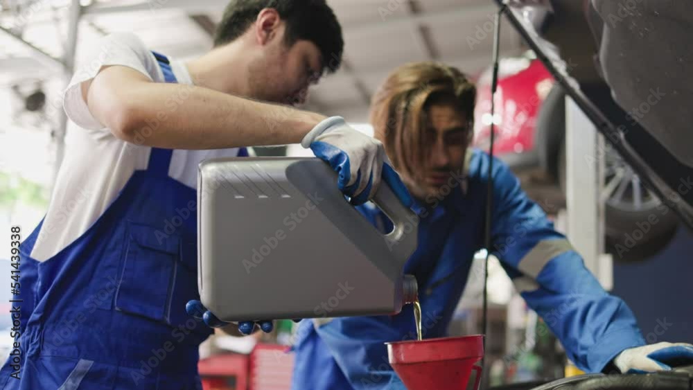 oil pouring, the car technicians are pouring oil into the car engine. concept: motor oil replacement at the car service station. oil pouring, the car technicians are pouring oil into the car engine. concept: motor oil replacement at the car service station.