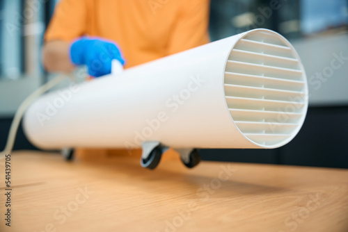 Cleaning worker uses an ozone generator while cleaning coworking space photo