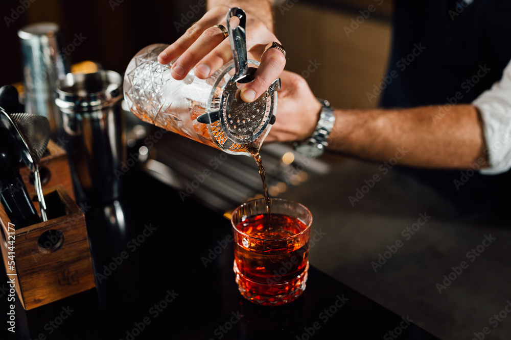 close up of barman pouring cocktail into glass