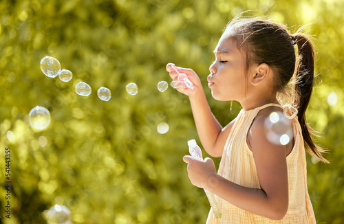 Bubbles, outdoor and girl in a nature park feeling relax, playful and content by sunshine. Child from Taiwan blow a bubble in the spring sun feeling peace, calm and content with happiness on vacation