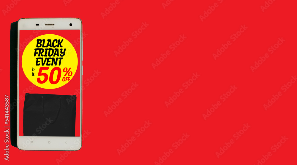 Word text black friday event up to 50% off written on yellow circle with black paper bag inside white smartphone isolated on red background. banner. copy space