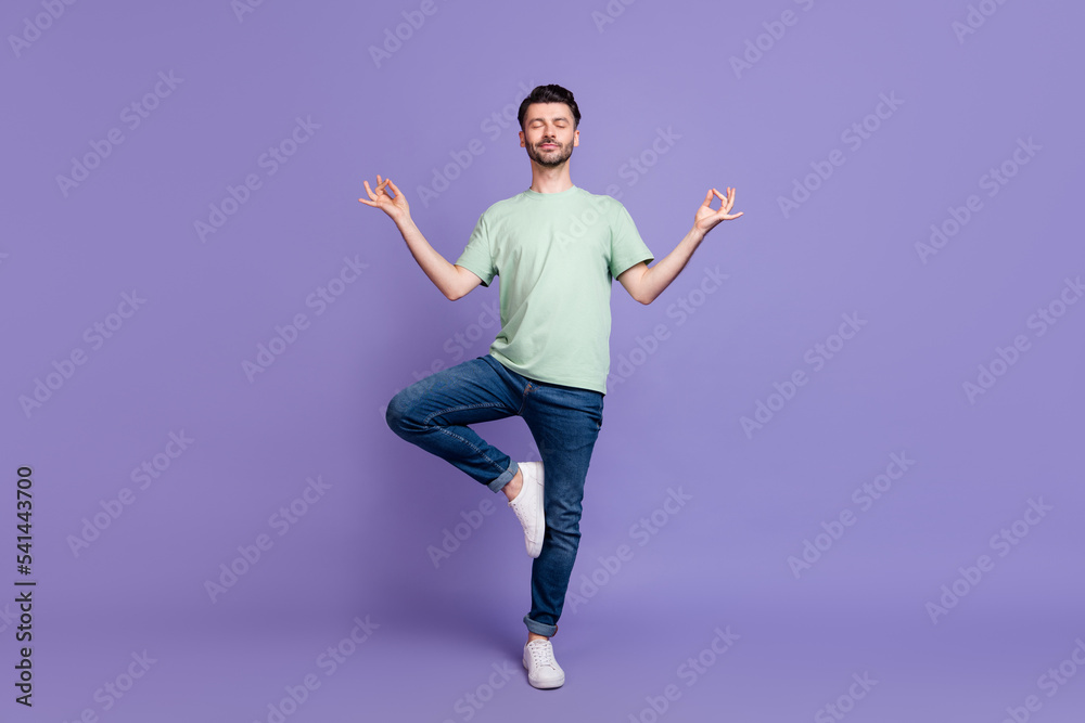 Full length photo of concentrated positive man wear denim stand one foot leg enjoy hobby time isolated on purple color background