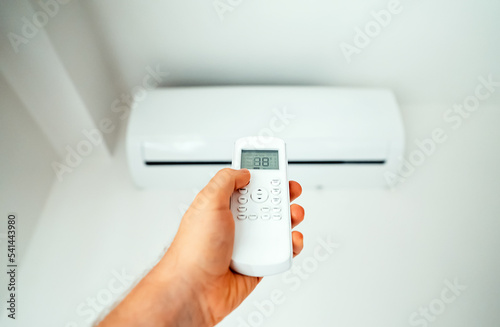 Obraz na plátne Hand holding remote control aimed at the air conditioner.