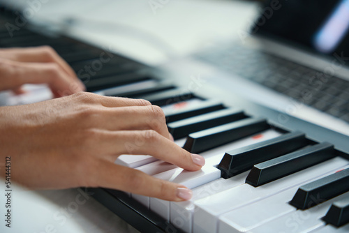 Woman pressing the black and white keys of musical instrument