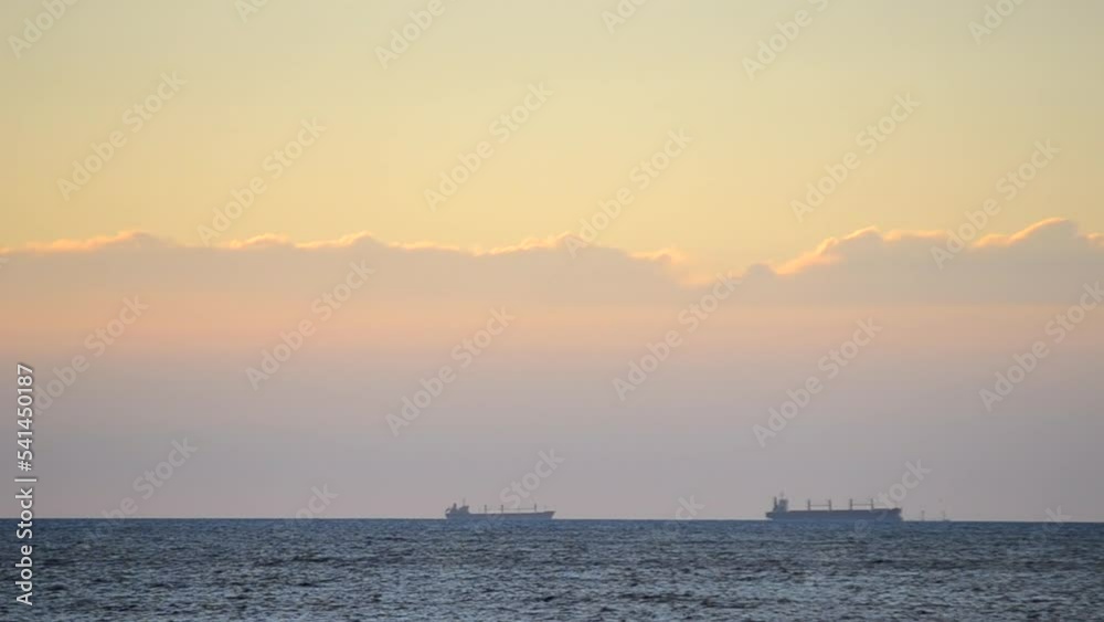 Timelapse. Silhouette of tankers of grain carriers on the skyline in the sea and fast moving clouds on yellow blue sky at dawn at sunset. Seascape, sea landscape. Transportation. Natural background Timelapse. Silhouette of tankers of grain carriers on the skyline in the sea and fast moving clouds on yellow blue sky at dawn at sunset. Seascape, sea landscape. Transportation. Natural background