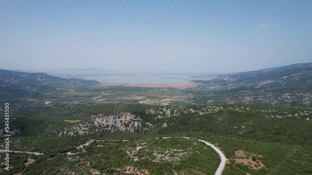 Aerial view of Karla lake in Greece surrounded by mountains. Drone shot flyover the road