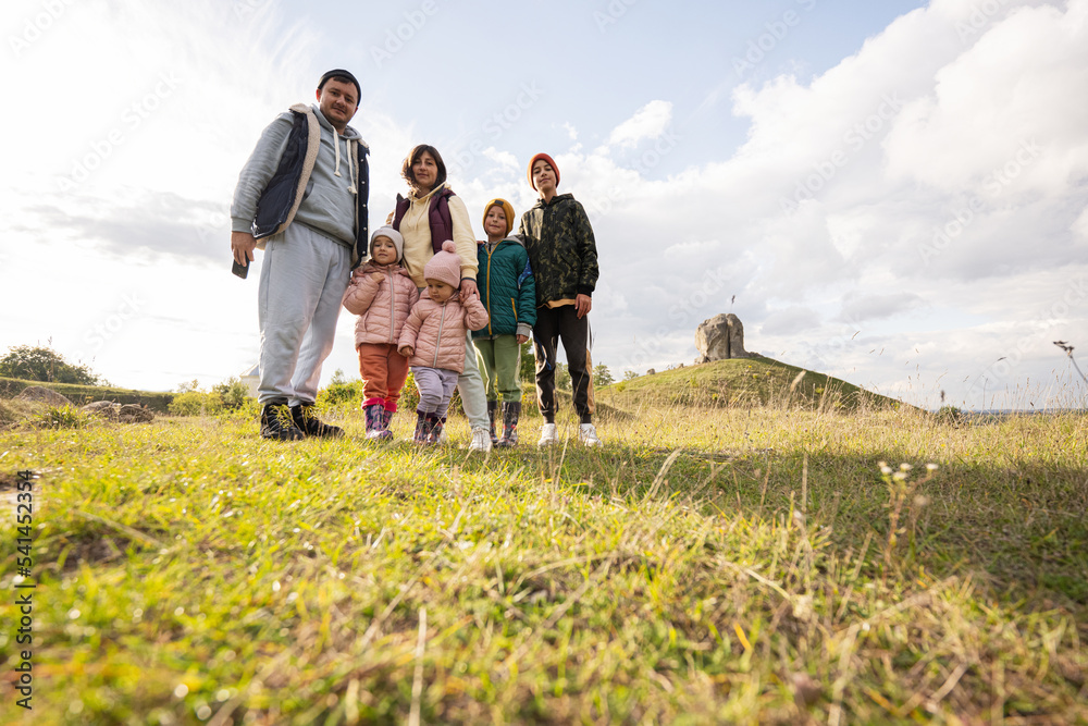 Family exploring nature. Children with parents stand against big stone in hill. Pidkamin, Ukraine. Family exploring nature. Children with parents stand against big stone in hill. Pidkamin, Ukraine.