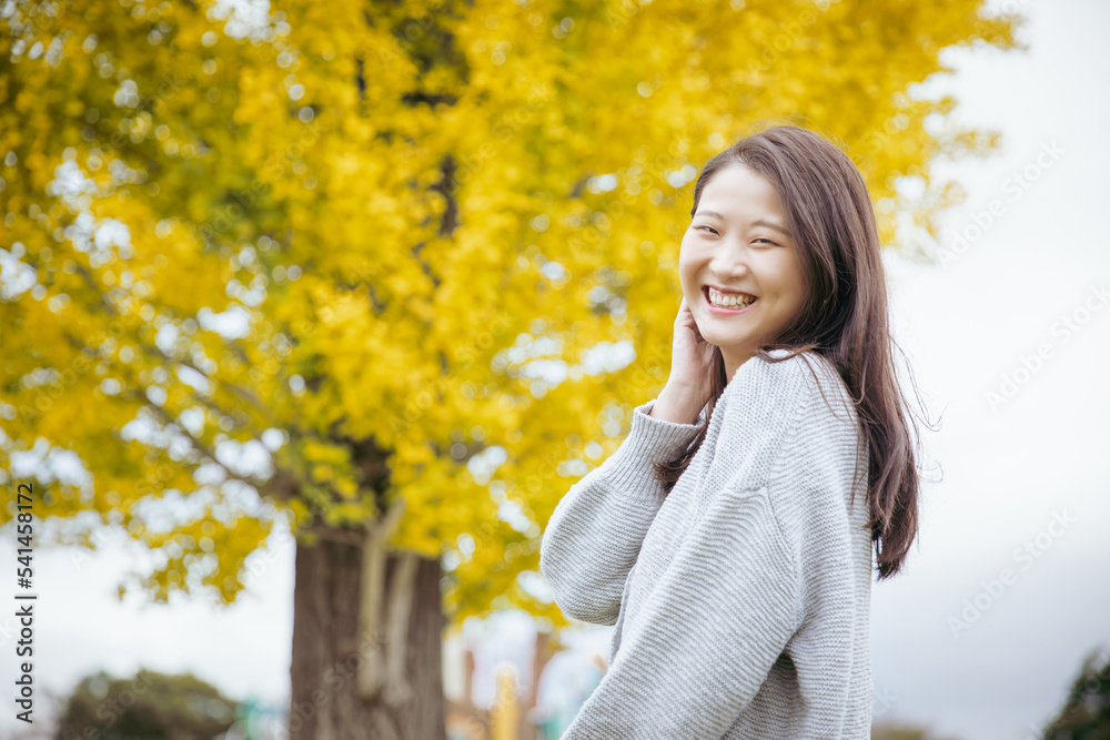 イチョウの木の前で笑顔でいる女性 ginkgo woman イチョウの木の前で笑顔でいる女性 ginkgo woman