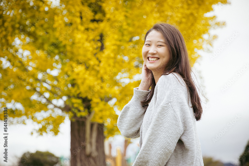 イチョウの木の前で笑顔でいる女性  ginkgo woman