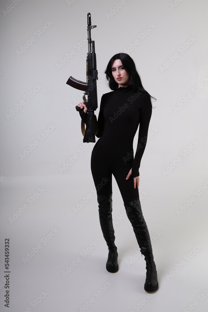 Beautiful slender brunette woman in black clothes with assault rifle Beautiful slender brunette woman in black clothes with assault rifle