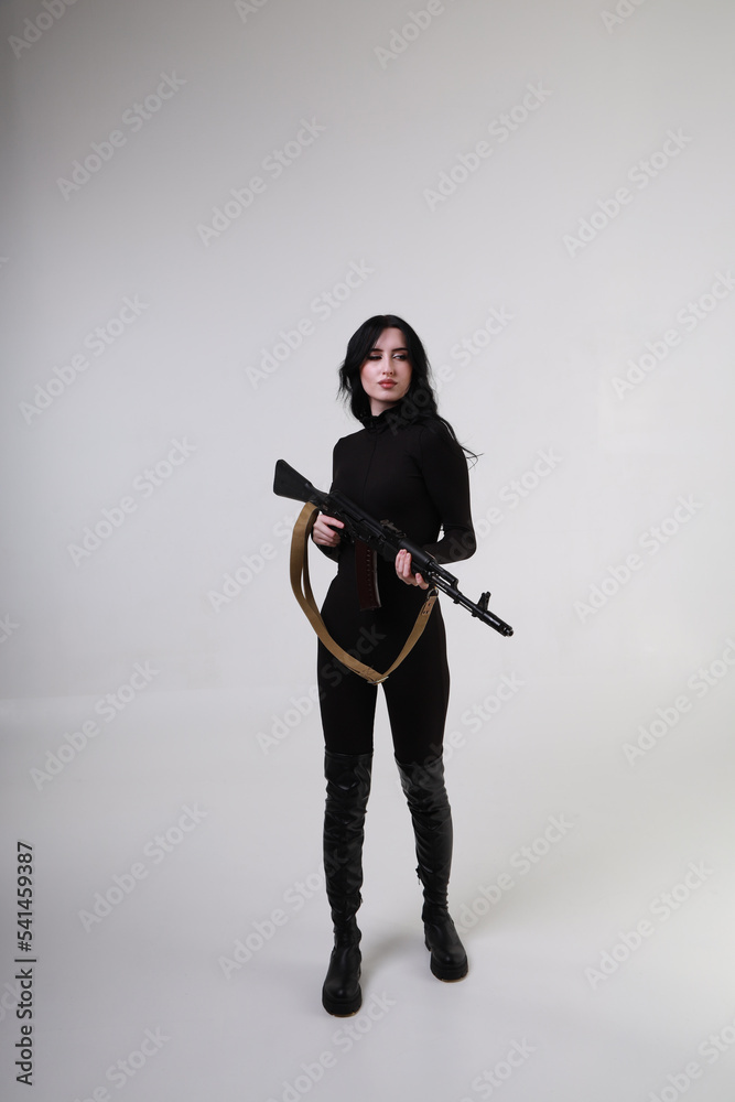 Beautiful slender brunette woman in black clothes with assault rifle Beautiful slender brunette woman in black clothes with assault rifle