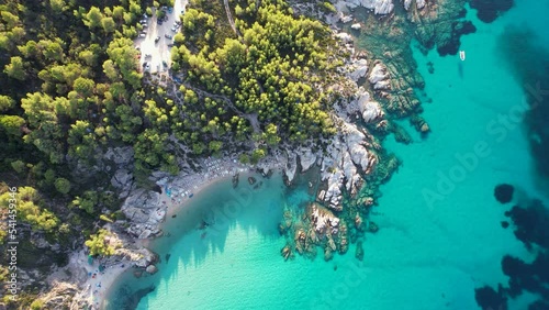 Aerial drone video of iconic turquoise and sapphire Paradise beach in Sithonia, Greece with the view on Atos mountain. Beautiful view of a sandy beach surrounded with high rocks photo