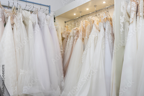 White and cream wedding dresses on a hanger in a bridal boutique. Close up © Serhii
