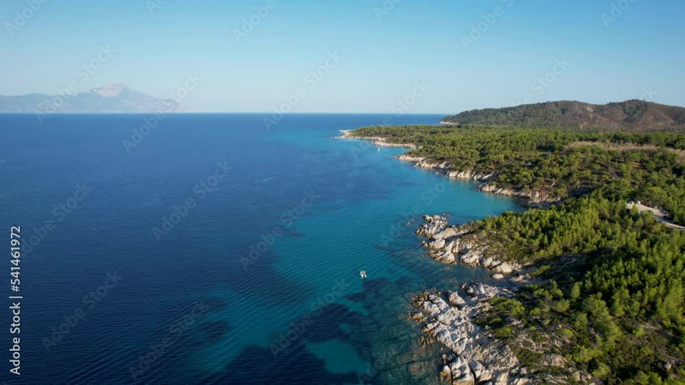 Aerial drone video of iconic turquoise and sapphire Paradise beach in Sithonia, Greece with the view on Atos mountain. Beautiful view of a sandy beach surrounded with high rocks Aerial drone video of iconic turquoise and sapphire Paradise beach in Sithonia, Greece with the view on Atos mountain. Beautiful view of a sandy beach surrounded with high rocks