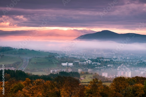 Foggy fall morning near Banska Bystrica. Landscape with forests and mountains around the city. Autumn colored trees at sunrise.