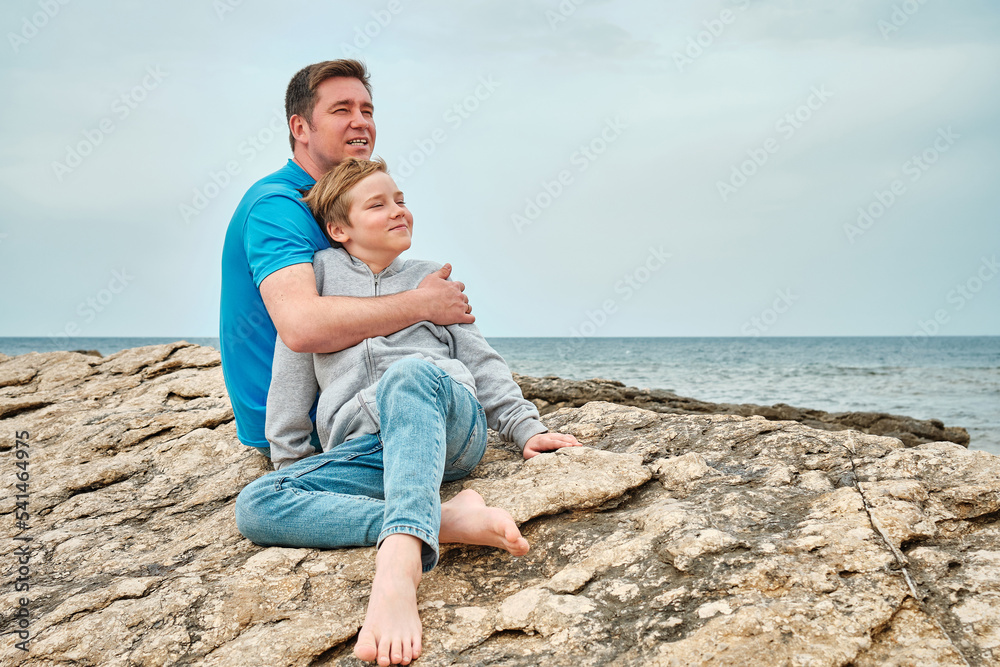 Happy family, father and son bonding, sitting on stone by the sea looking at view enjoying summer vacation. Togetherness Friendly concept
Happy family, father and son bonding, sitting on stone by the sea looking at view enjoying summer vacation. Togetherness Friendly concept