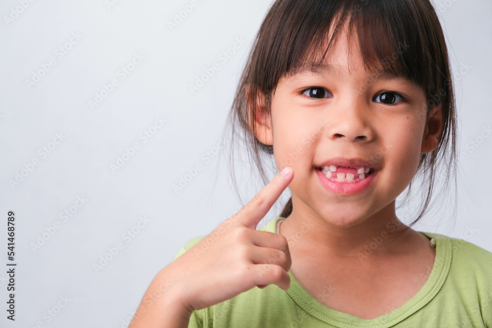 Portrait of an Asian girl with broken upper baby teeth and first permanent teeth. Friendly little girl showing her broken teeth isolated on white background. Portrait of an Asian girl with broken upper baby teeth and first permanent teeth. Friendly little girl showing her broken teeth isolated on white background.