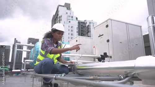 Female engineer inspects and controls the cooling system of a large factory air conditioner.