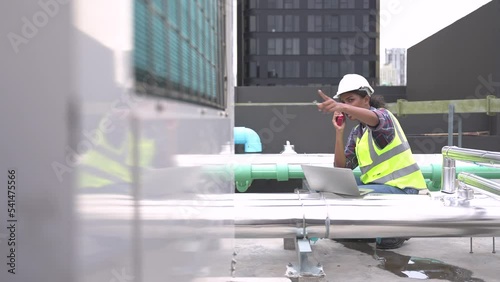 Female engineer inspects and controls the cooling system of a large factory air conditioner.