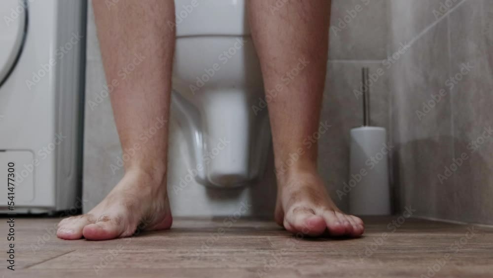 A man goes to the toilet in the toilet, takes off his denim shorts and ...