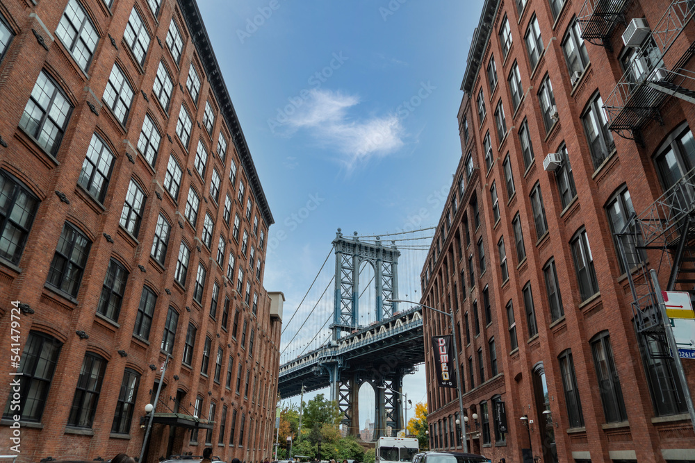 Manhattan Bridge between Manhattan and Brooklyn over East River seen from a narrow alley enclosed by two brick buildings in in Dumbo, Brooklyn, new york city