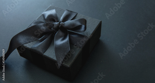Black Friday Sale. Gift box with black ribbon isolated on black, close up