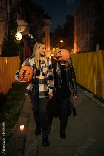 A mother with her teenage daughter walks in the evening in the city with pumpkins