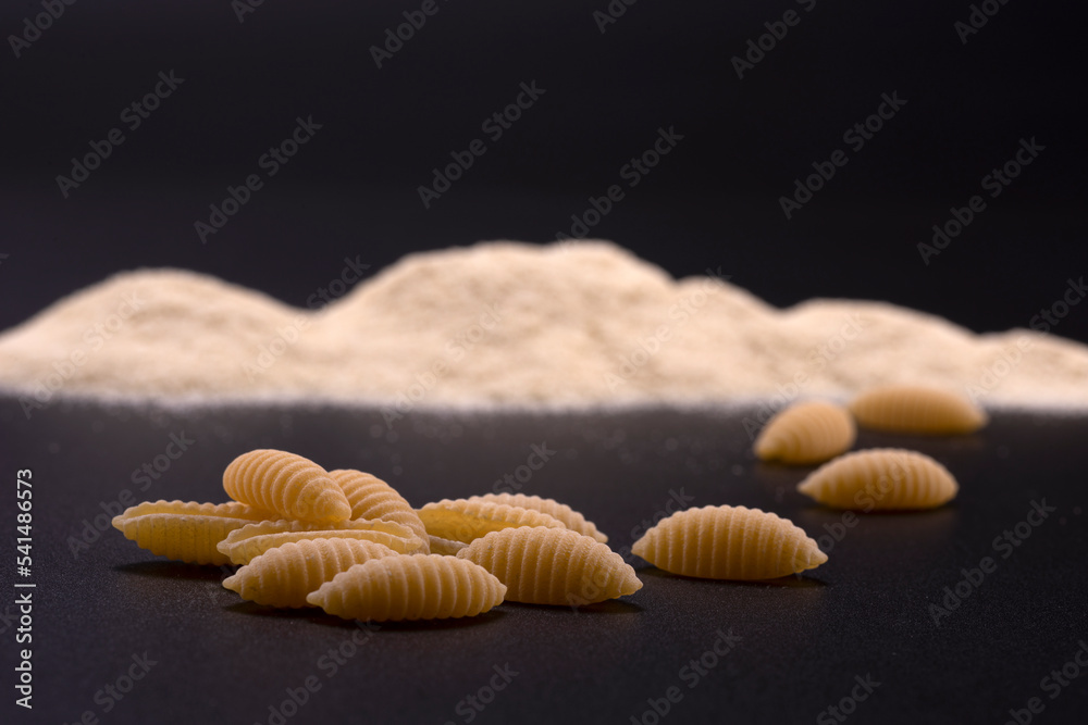 Typical Sardinian pasta gnocchi with semolina flour on a black background