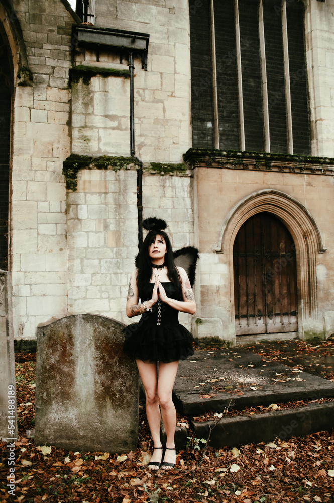 Woman dress up as a sexy fallen angel in a cemetery, Halloween
