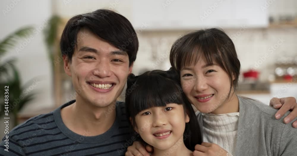 closeup portrait of loving asian father, mother and schoolgirl daughter smiling at camera at home. they cuddle with each other feeling happiness closeup portrait of loving asian father, mother and schoolgirl daughter smiling at camera at home. they cuddle with each other feeling happiness