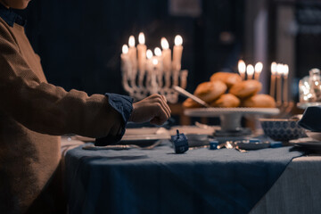 Food for Hanukkah celebration: Menorah Candles on wooden table, sufganiyot cake and table setting, jewish symbol centerpieces, white and blue. holiday Israel hebrew traditional family celebration