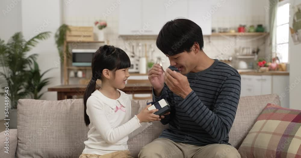 slow motion of happy surprised asian dad hugging his daughter after releasing hand covering face and seeing the fatherâs day gift in the living room at home slow motion of happy surprised asian dad hugging his daughter after releasing hand covering face and seeing the fatherâs day gift in the living room at home