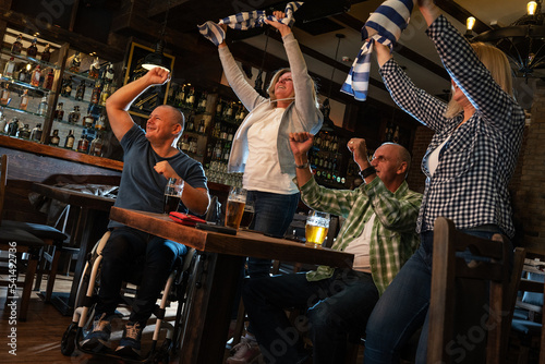 Senior football and soccer fans drinking beer at the pub, cheering and celebrating scores. 