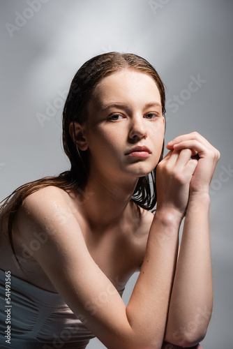 Young model with wet hair posing on grey background