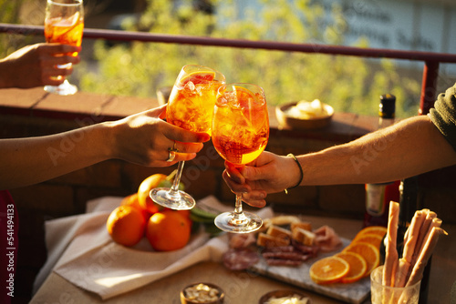 Photography Two hands with glasses of Aperol Spritz cocktail in the sunset summer