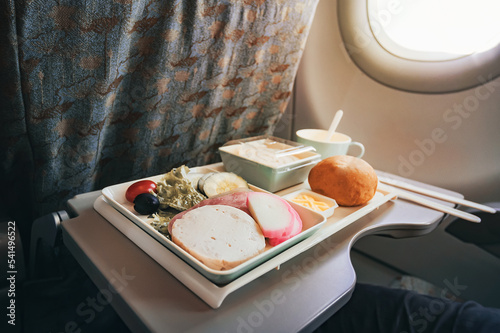 Inflight meal service tray for economy class, meat, fruit, salad, cucumber, a glass of juice and butter. fork knife made of plastic for safety.