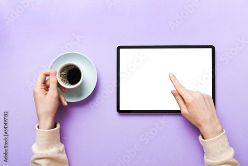 Close up image woman hands holding digital tablet with blank copy space screen for your text message or promotional content om table with cup of coffee. hands of a woman holding blank tablet device