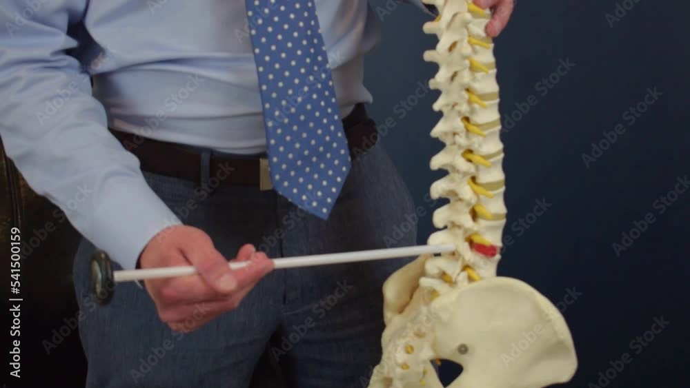 Man in a suit points to the construction of a human skeleton in his hand