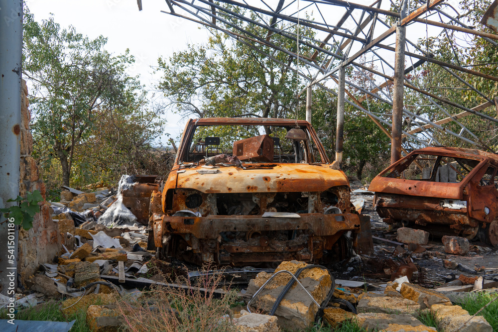 War in Ukraine. 2022 Russian invasion of Ukraine. Countryside. A destroyed, burned-out civilian car stands in the courtyard of a destroyed house. No people. War crimes