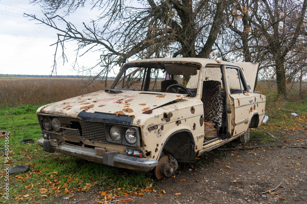 War in Ukraine. 2022 Russian invasion of Ukraine. Countryside. A destroyed civilian car stands on the side of the road. Holes from bullets and splinters on the body of the car