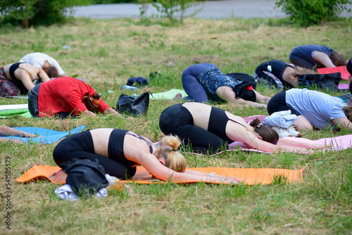 Group of young women doing morning exercises on carimates in the city park. Kyiv, Ukraine