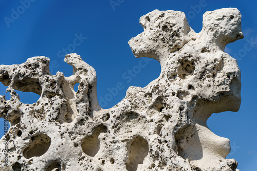 An old stone of complex shape against the background of a blue sky
