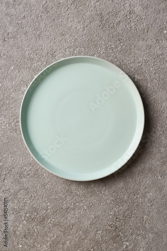 empty light plate on a gray concrete background, top view, copy space