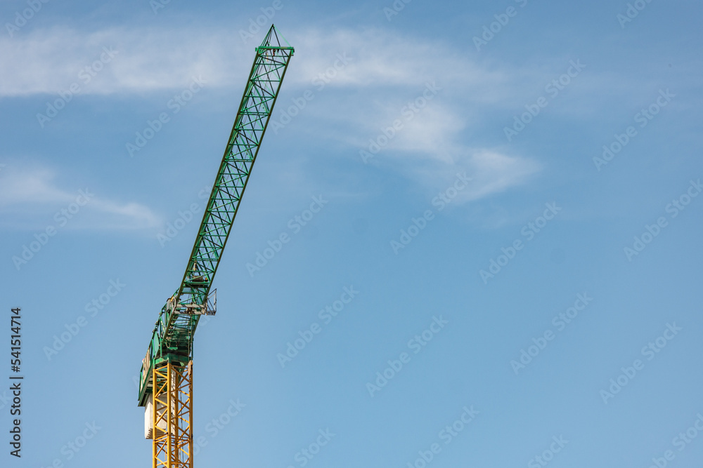 Yellow construction crane with green arm against a clear sky Yellow construction crane with green arm against a clear sky