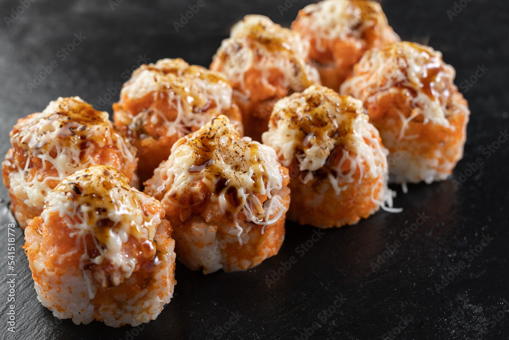 Japanese Baked sushi over black stone background. Tasty and artistic food for restaurant or cafe menu. Rolls on the dish. Japanese cuisine. Sushi menu Japanese Baked sushi over black stone background. Tasty and artistic food for restaurant or cafe menu. Rolls on the dish. Japanese cuisine. Sushi menu