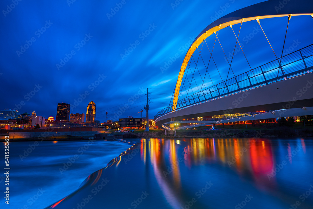 Obraz premium Des Moines River walk bridge reflected in the Des Moines River during blue hour. Des Moines, Iowa. 