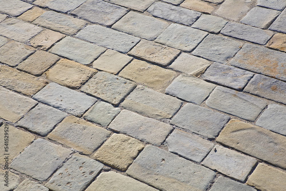 Old and damaged italian paving made with chiseled grey sandstone