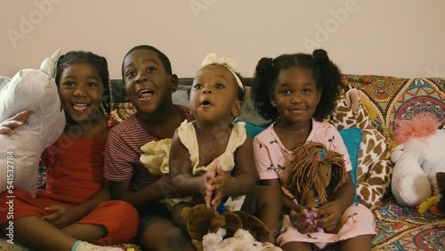 Black family with Black mother, Black father, Black daughters, Black son, and a Black infant baby girl having fun at home